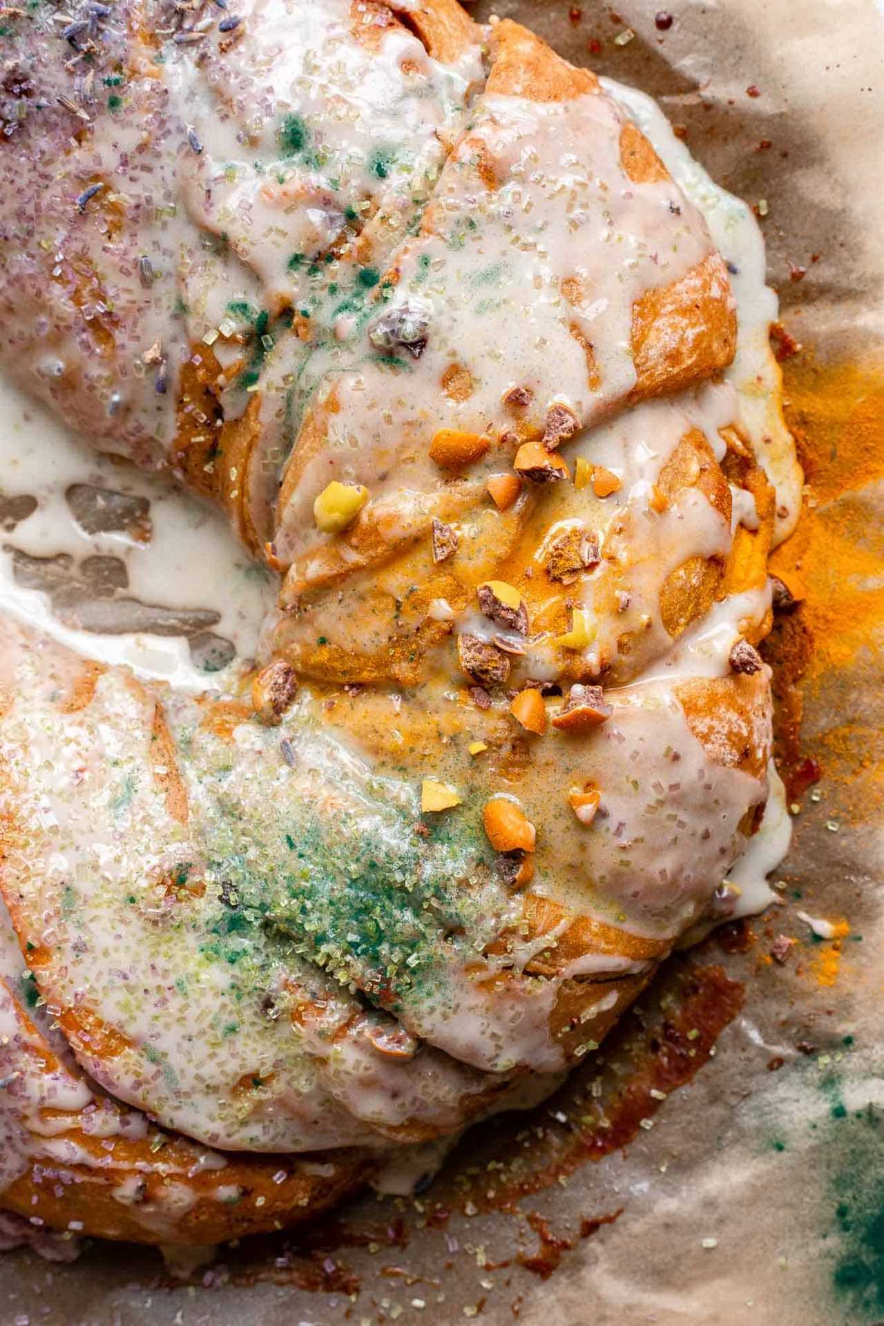 close up view of sourdough king cake with a braided texture, white icing and gold sprinkles