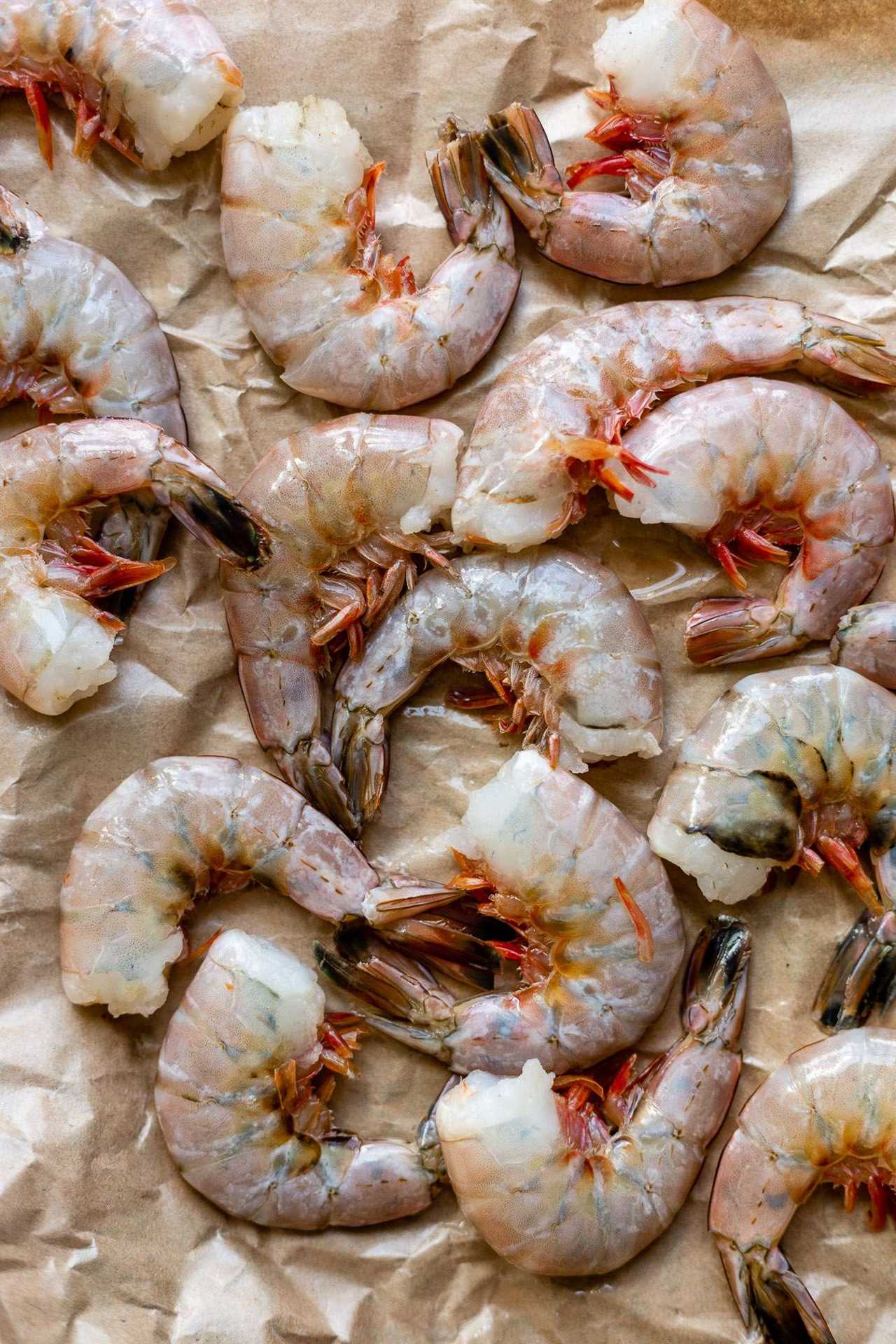 Large gulf shrimp tails with the peel still on on top of brown crinkly butcher paper. 