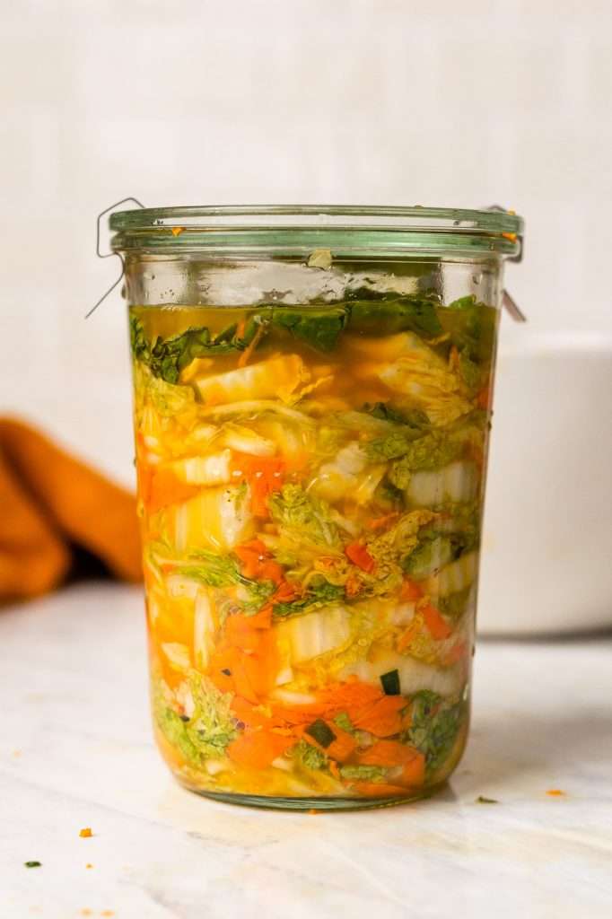 Turmeric sauerkraut made with napa cabbage and carrots in a glass jar. The turmeric has turned the cabbage bright gold. 