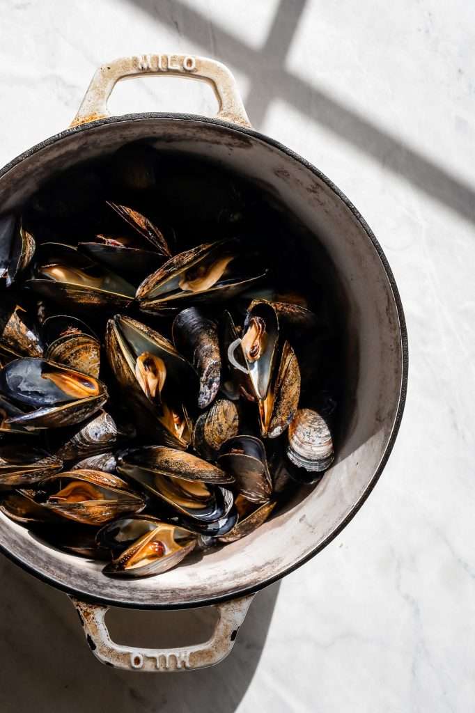black mussels steamed with the shells open in a large pot.
