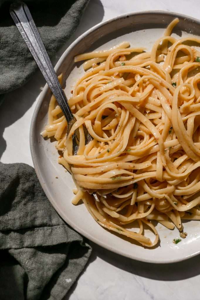 cheesy miso pasta on a white plate with a silver fork
