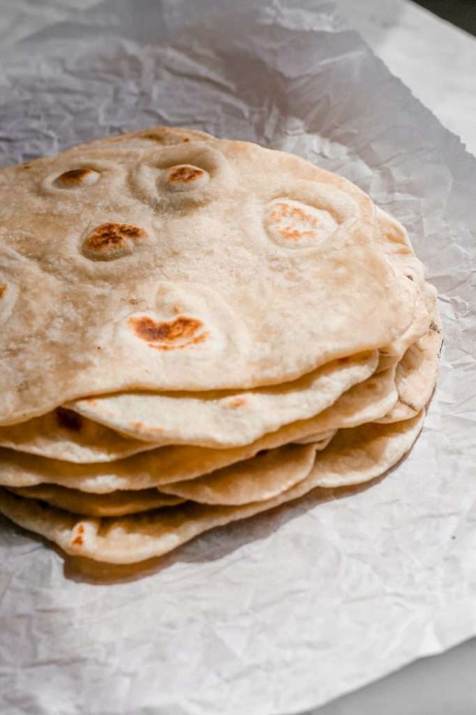 sourdough tortillas stacked on a piece of wrinkly parchment paper