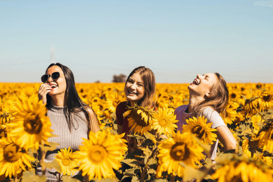 group of women smiling and laughing in a sunflower field