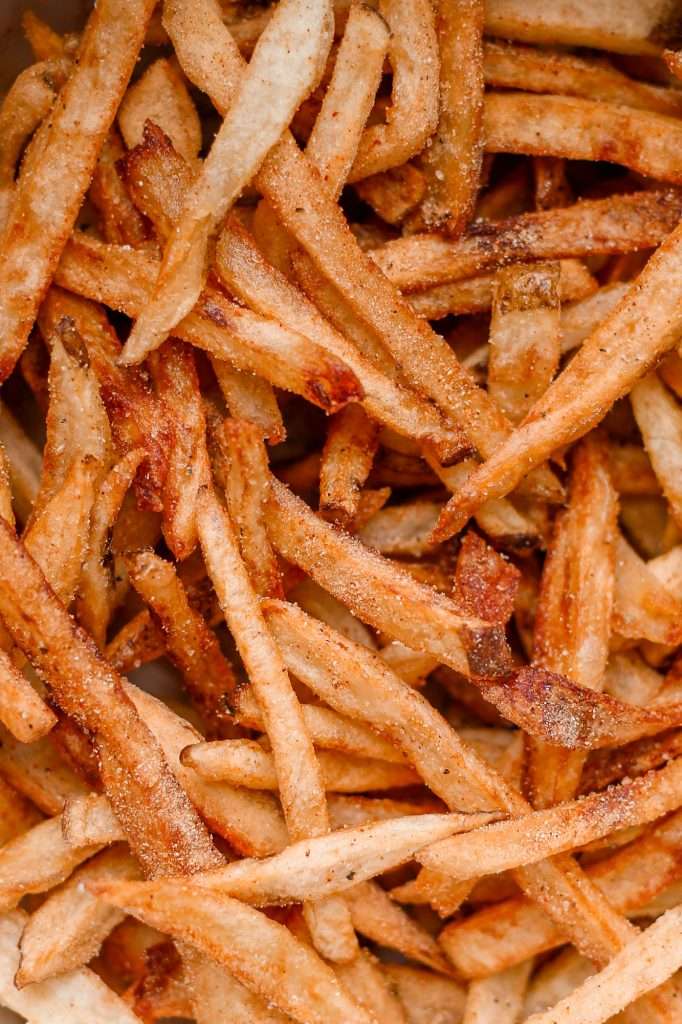 close up of lemon pepper fries fried in duck fat until golden brown and crispy. These is a fine dusting of lemon pepper and salt on the fries. 