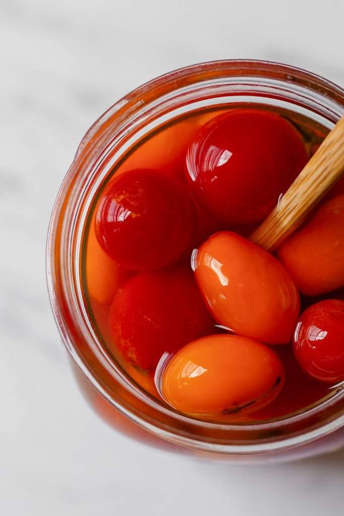 plump cherry tomatoes in a jar on the first day of vinegar fermentation. 