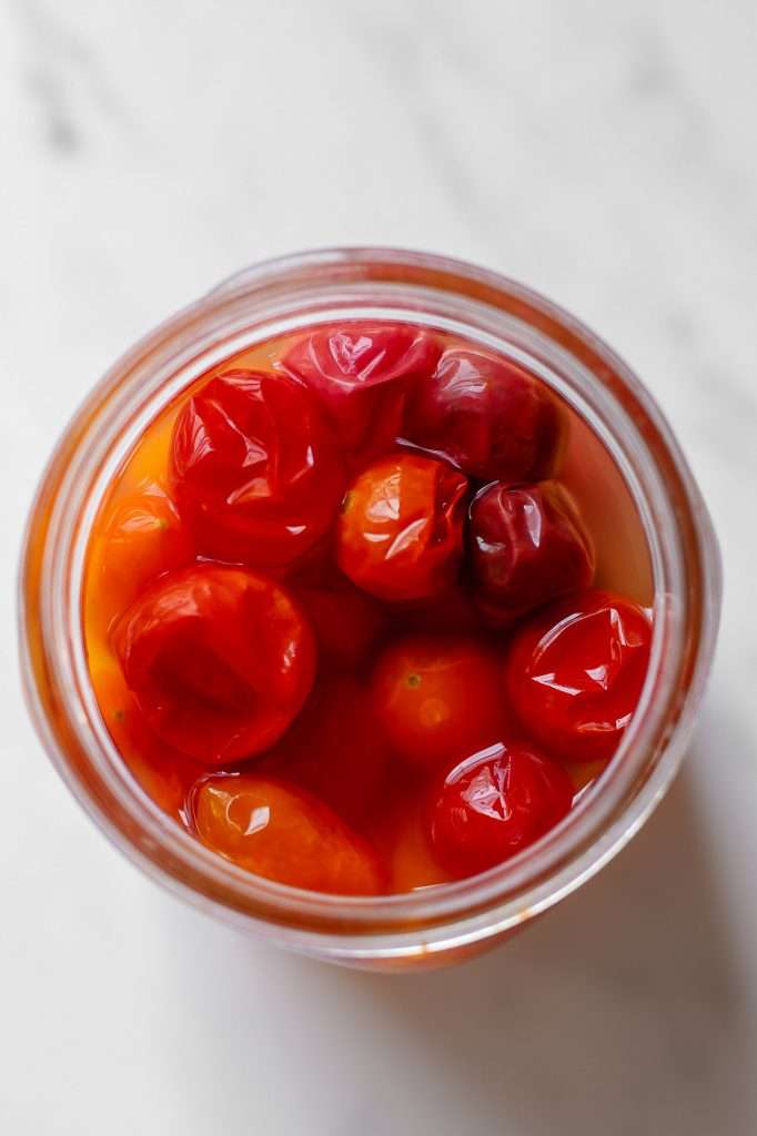 wrinkly, deflated, cherry tomatoes in a jar of cherry tomato vinegar after three weeks of fermentation. 