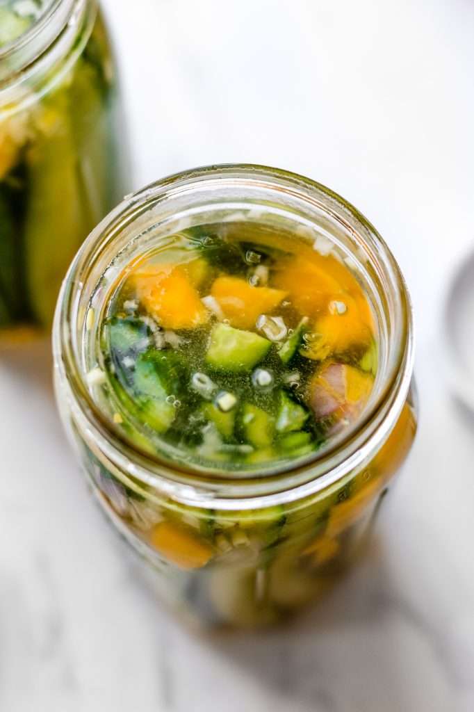 a glass fermentation weight in a jar of mango chili probiotic pickles. 